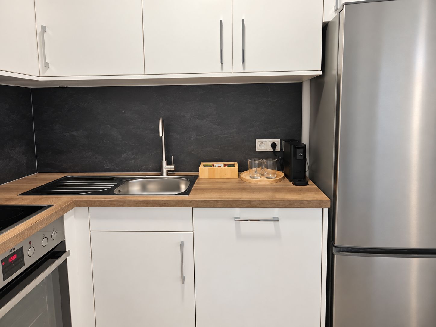 Eine moderne Küche mit einem Edelstahl-Kühlschrank, einem Einbauofen und einer Spüle mit einer Holzarbeitsplatte.