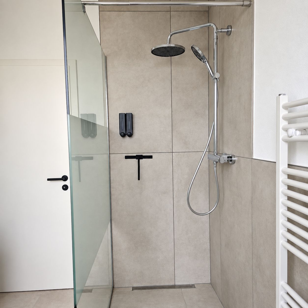 Eine moderne Duschkabine mit Glastür, Handbrause und einer fest montierten Bedienkonsole.