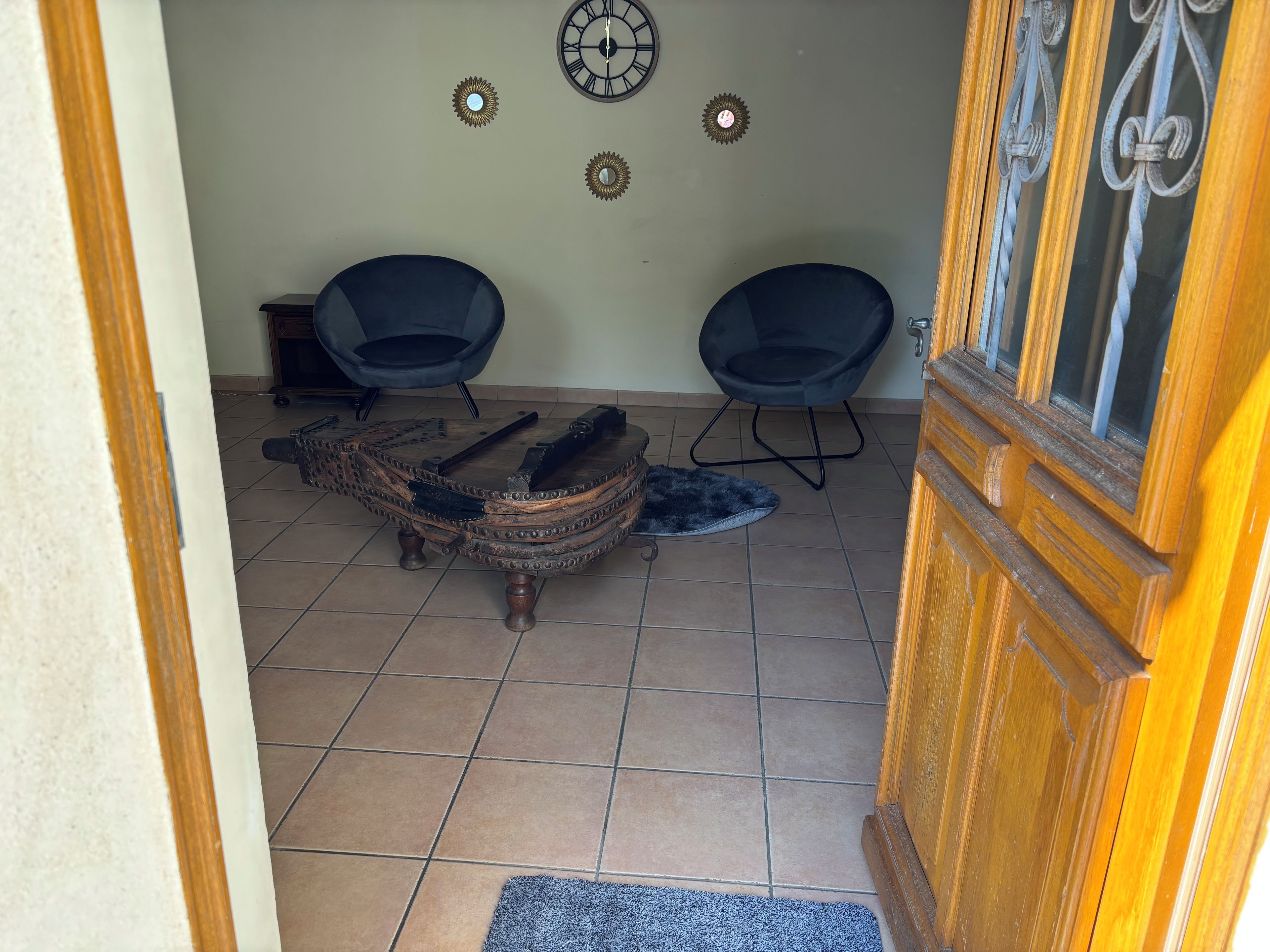 Ein Zimmer mit zwei schwarzen Stühlen, einem rustikalen Holztisch und einer Tür mit Fensterteil.