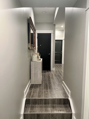 A modern hallway with a dark wood floor, a white console table with a vase, and a black door at the end. - Apartment Oasis, 1 br plus office and spa bath in Chicago near public transport (Chicago)