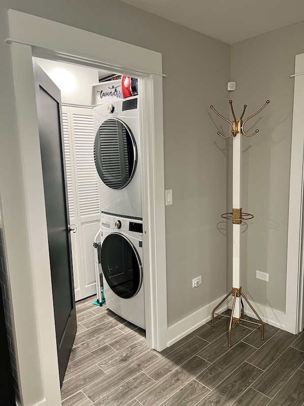 A laundry room with two stacked front-loading washing machines, a coat rack, and a door leading to another room. - Apartment Oasis, 1 br plus office and spa bath in Chicago near public transport (Chicago)