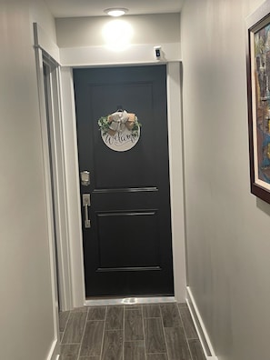 A hallway with a dark door featuring a welcome sign, a light fixture above, and a framed picture on the wall. - Apartment Oasis, 1 br plus office and spa bath in Chicago near public transport (Chicago)