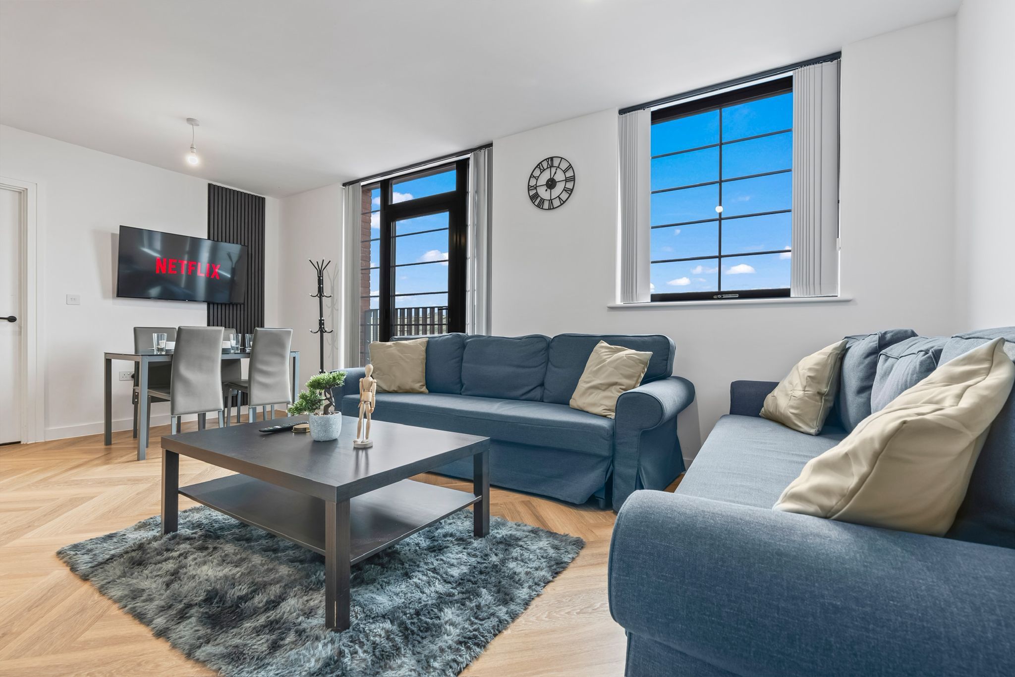 A modern living room with a sofa, a coffee table, a TV, and a large window.