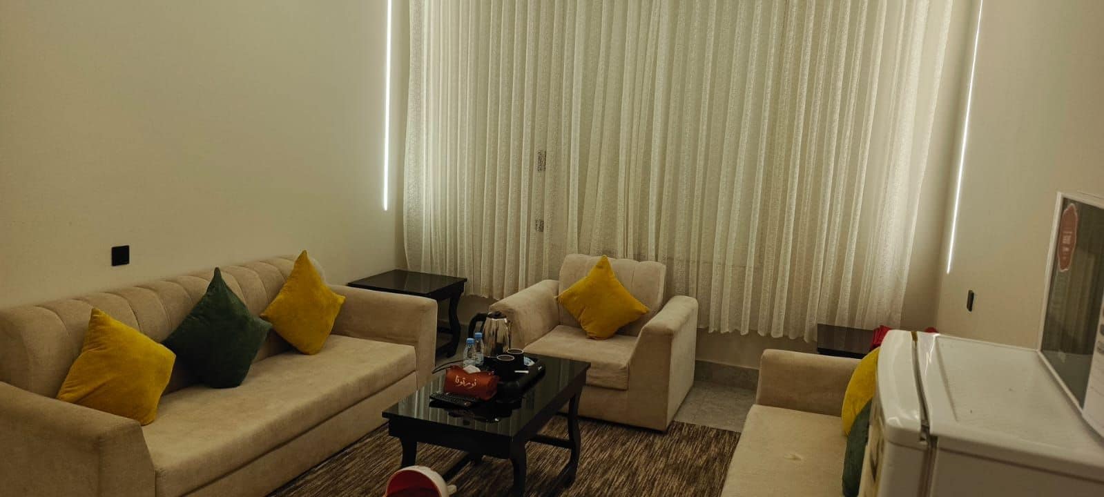 Ein Wohnzimmer mit einer Couch, einem Sessel, einem Couchtisch und einem kleinen Kühlschrank.