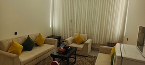 Ein Wohnzimmer mit einer Couch, einem Sessel, einem Couchtisch und einem kleinen Kühlschrank.