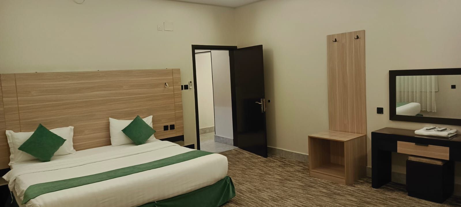 Ein Hotelzimmer mit Bett, Schreibtisch, Spiegel und Kleiderschrank.