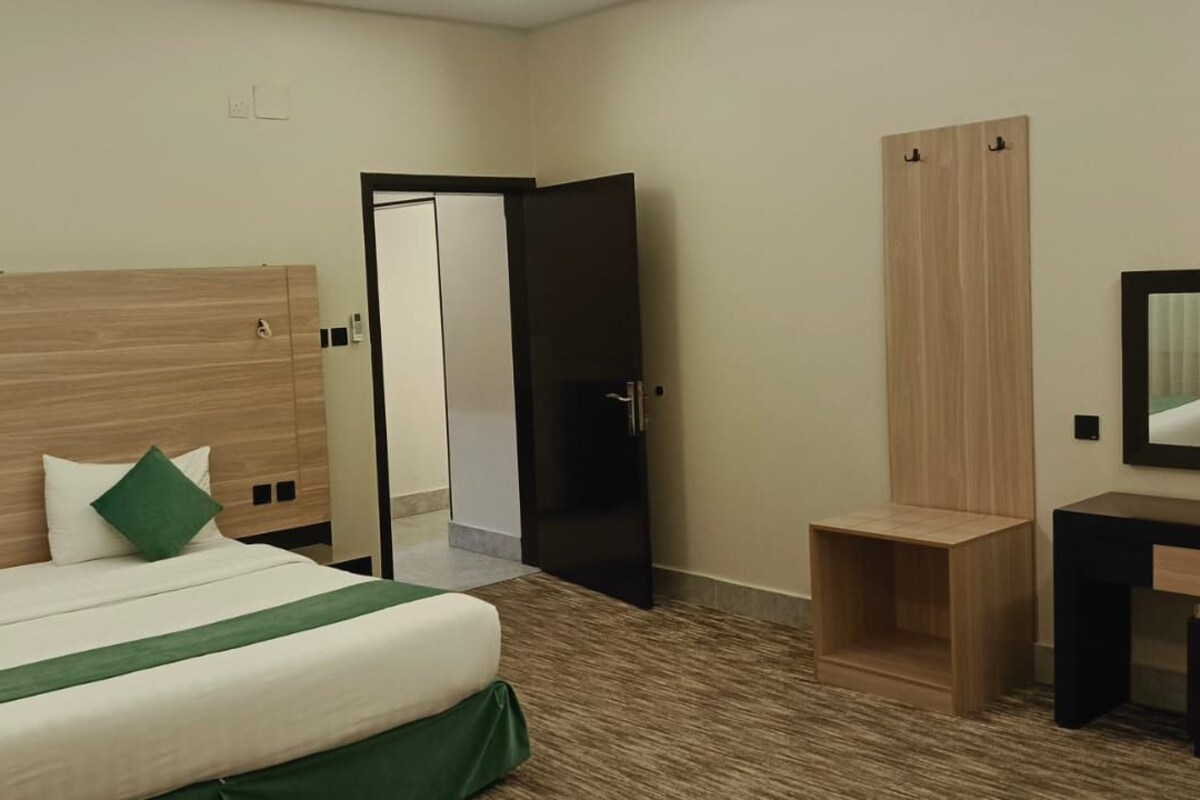 Ein Hotelzimmer mit Bett, Schreibtisch, Spiegel und Kleiderschrank.