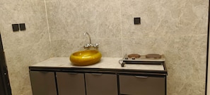 Ein Badezimmer mit Marmorfliesen, einem gelben Waschbecken und einer kleinen Ablage mit einer Seifenschale.