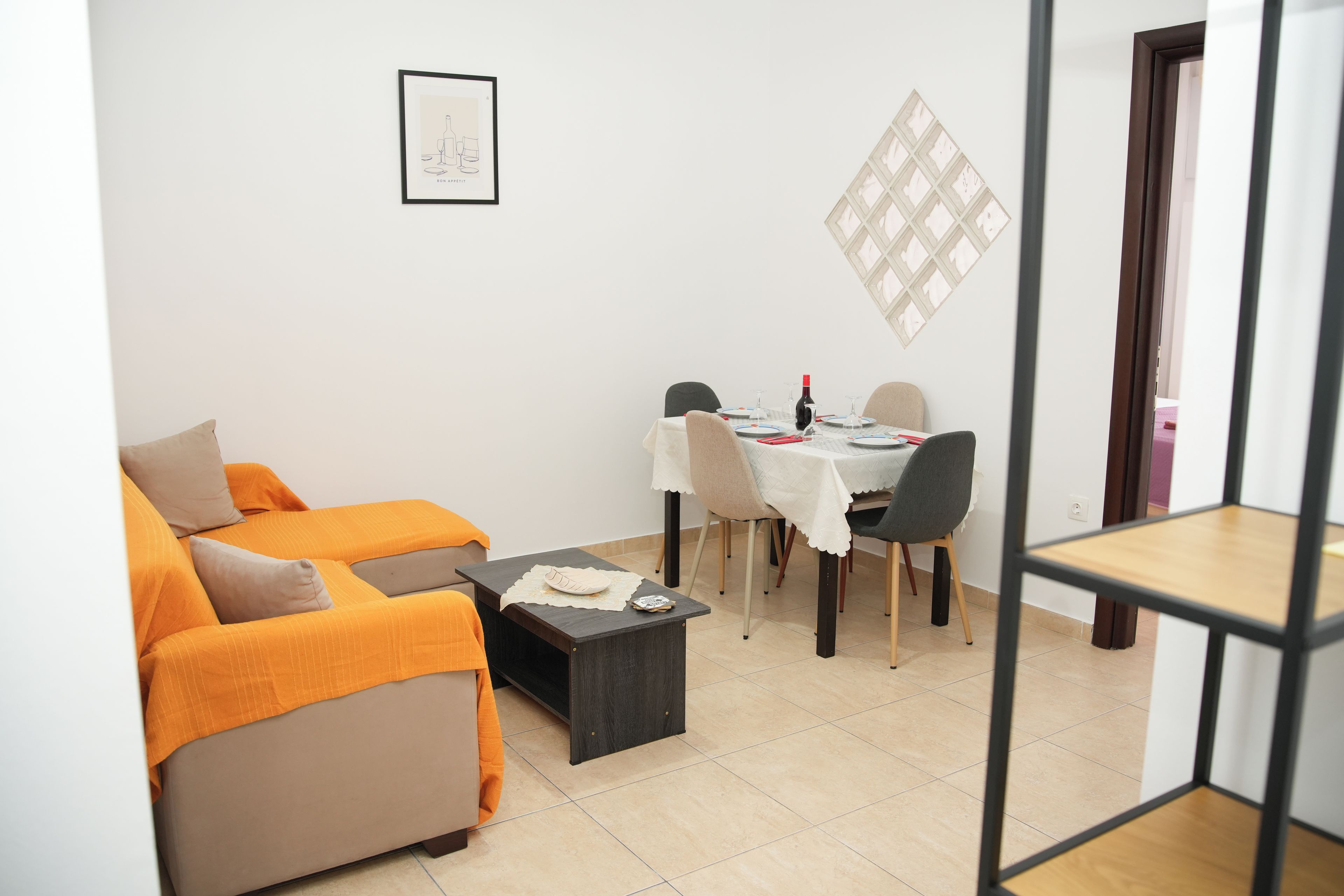 Una sala de estar con un sofá, una mesa de comedor para dos personas y un cuadro en la pared.