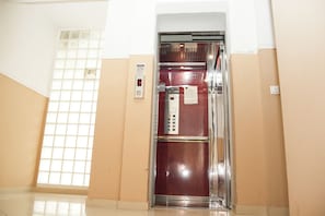 Un ascensor con pantalla digital, botón de contacto de emergencia y panel de control con botones.