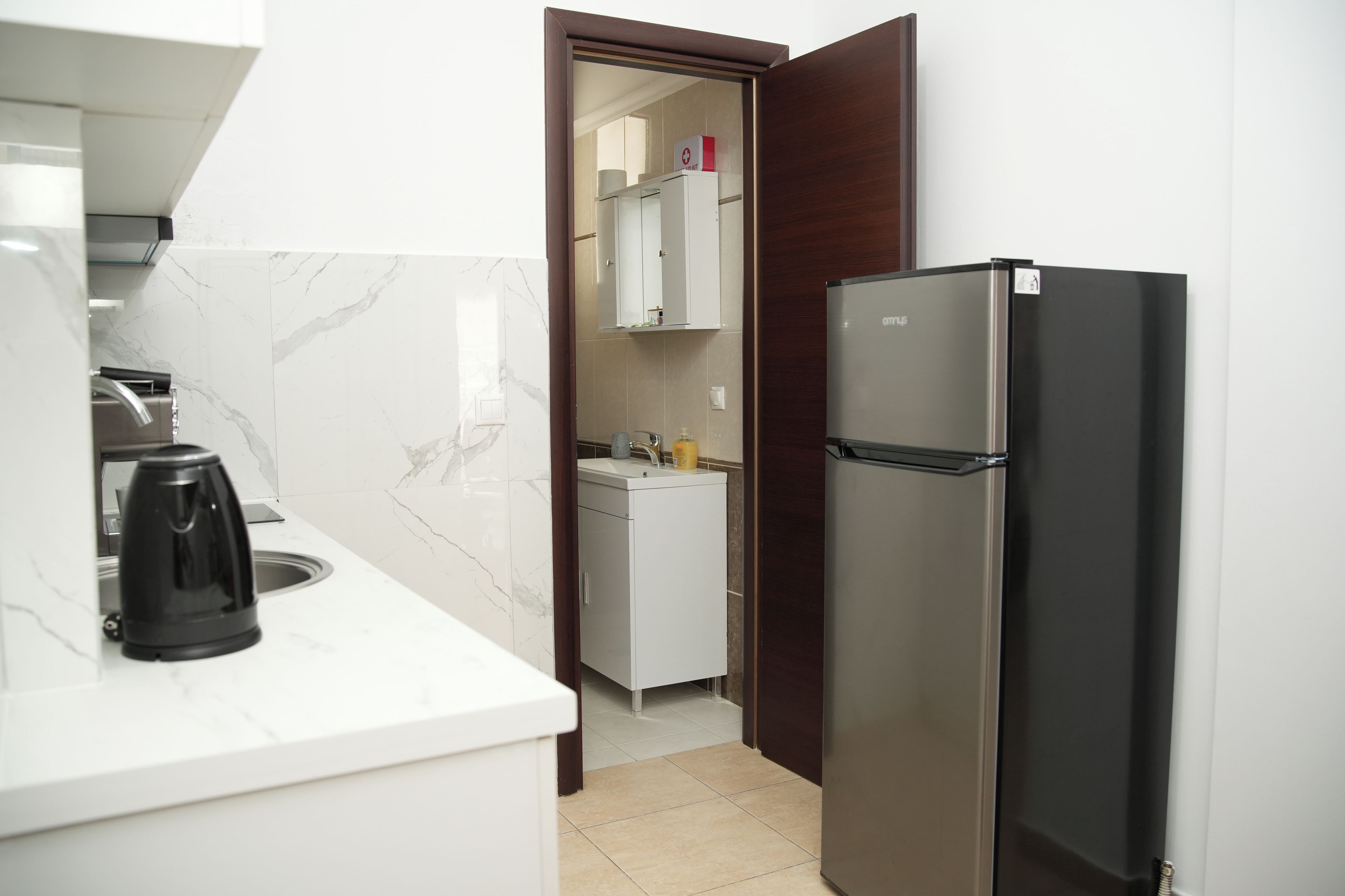 A compact kitchen with a refrigerator, a coffee maker, and a sink.