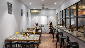 A conference room with a whiteboard, tables, chairs, and a bar area with a laptop.