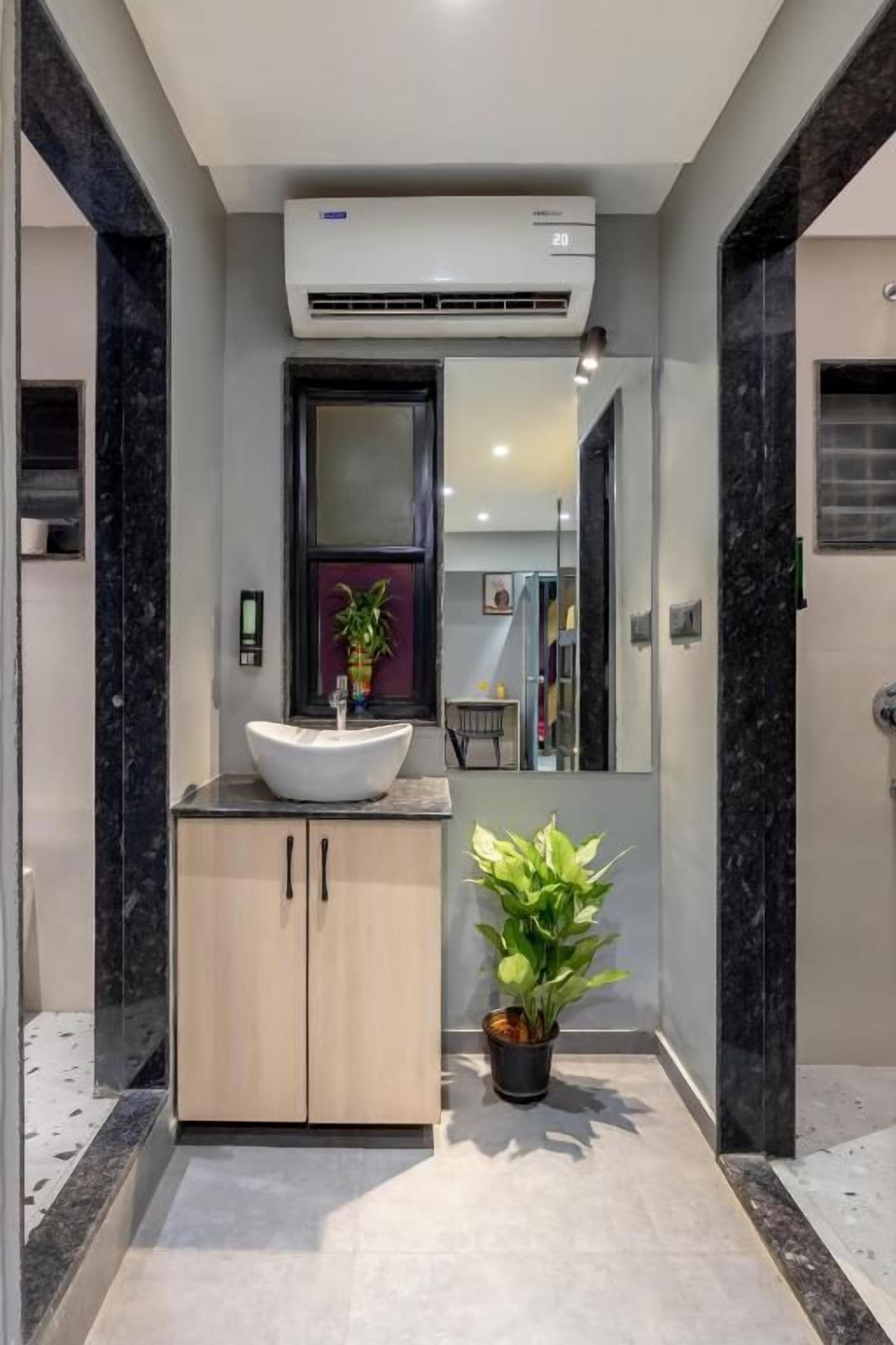 A modern bathroom with a freestanding sink, a potted plant, and a large mirror.