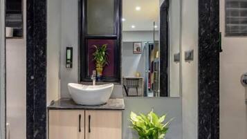 A modern bathroom with a freestanding sink, a potted plant, and a large mirror.