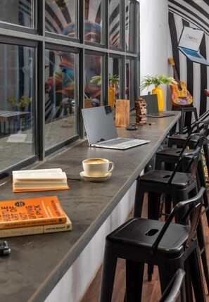 Un espace de travail moderne avec un ordinateur portable, des livres et une tasse de café posés sur un comptoir.