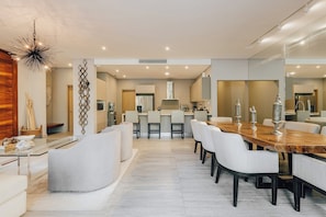 A modern dining area with a long wooden table, white upholstered chairs, and decorative metal vases. - Private Whirlpool Terrace - Gated 3BR Playacar, Beach + Town (Playa del Carmen)