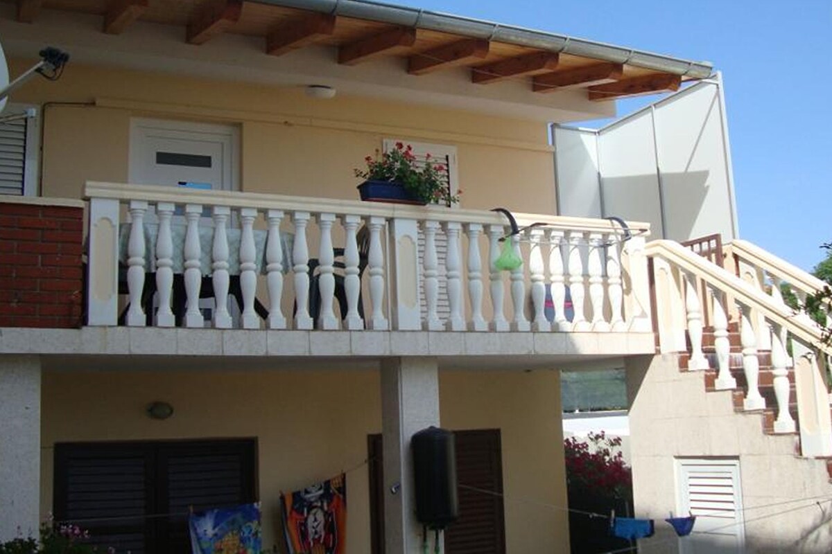 A two-story building with a balcony, a window, and a door.