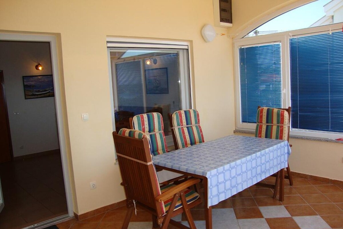 A dining area with a table and chairs, a window with blinds, and a view of the outside.