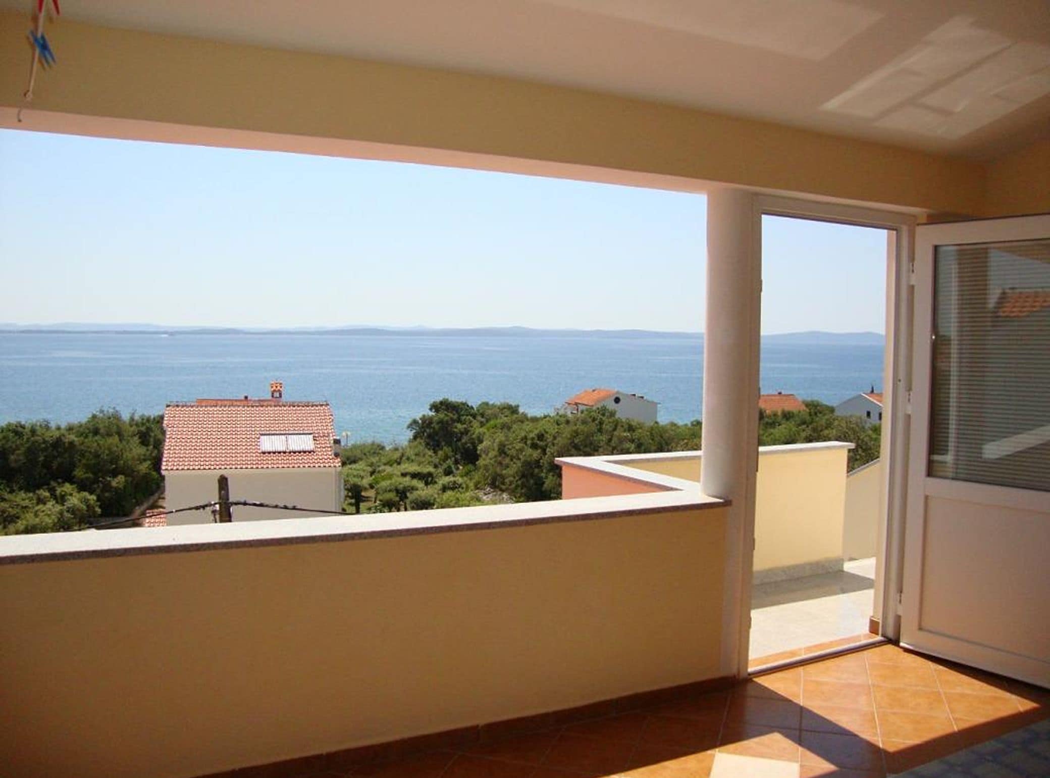 A balcony with a view of the sea and distant mountains.