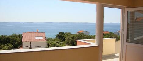 A balcony with a view of the sea and distant mountains.
