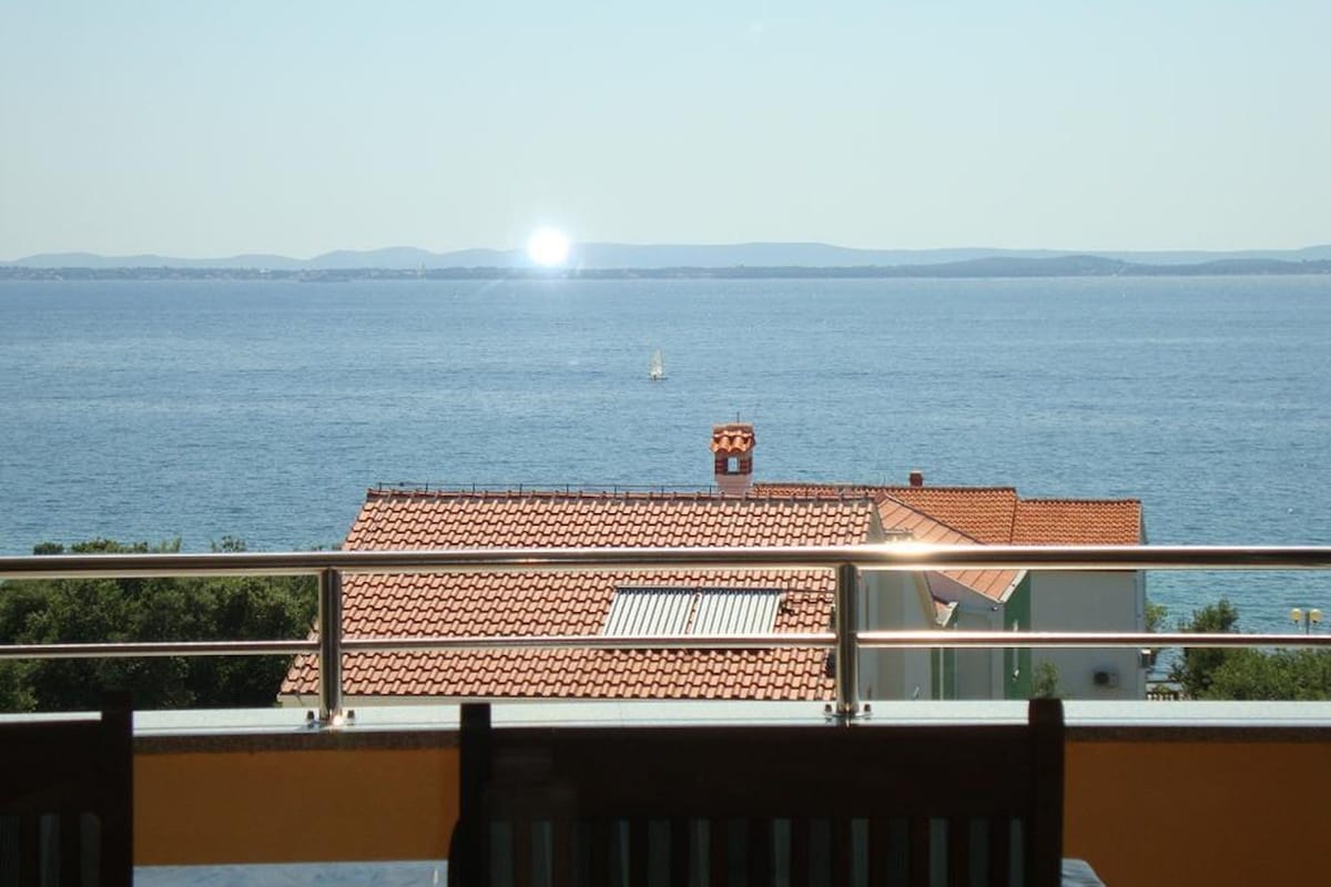 A view of a coastal area with a clear sky, a body of water, and a distant landmass.