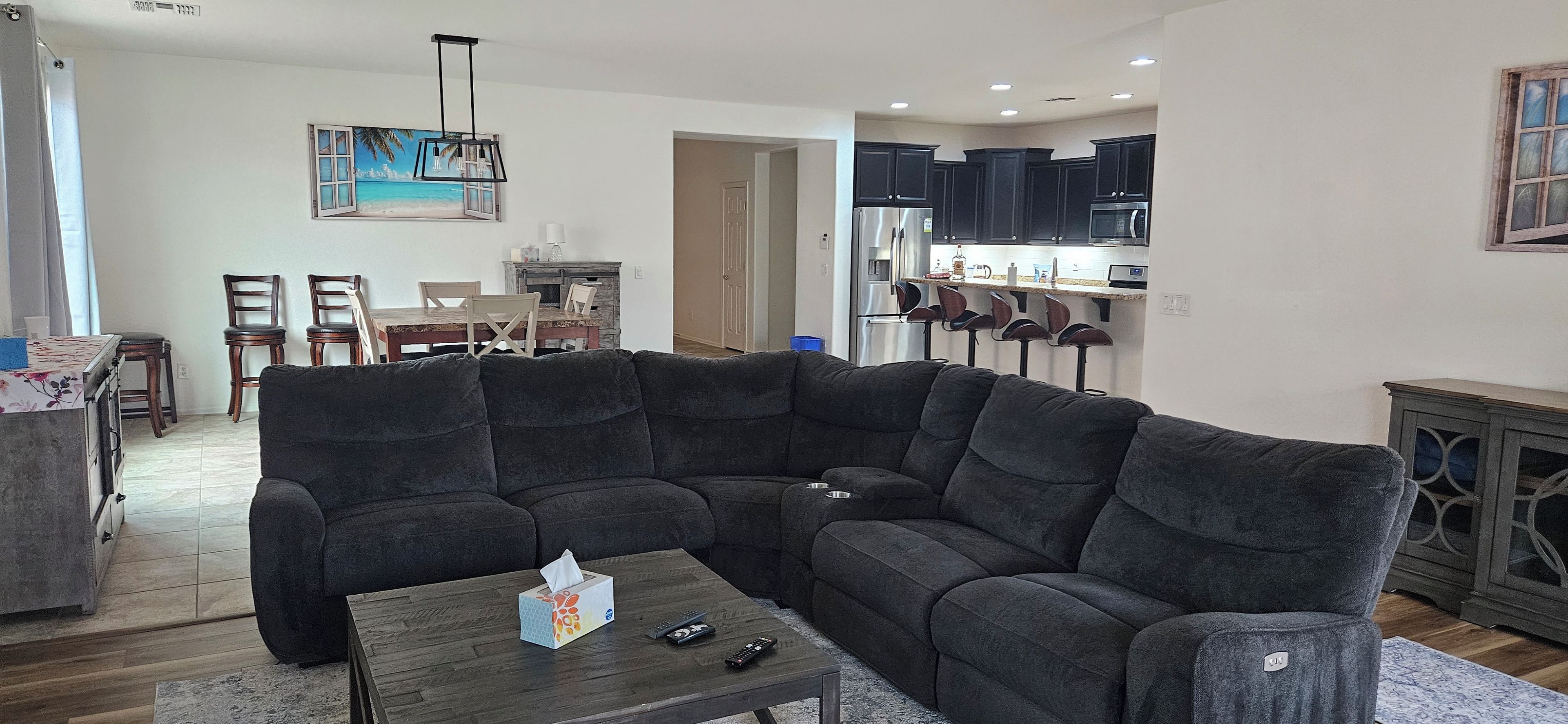 A living room with a sectional sofa, a coffee table, and a dining area with chairs and a table.