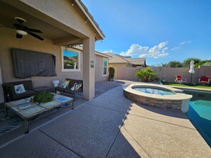 A residential backyard with a swimming pool, outdoor seating, and a covered patio area. - 3-bedroom house in gorgeous Surprise with cool AC breeze (Surprise)