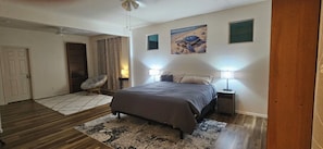 A bedroom with a bed, two bedside lamps, a chair, a door, and a window. - 3-bedroom house in gorgeous Surprise with cool AC breeze (Surprise)