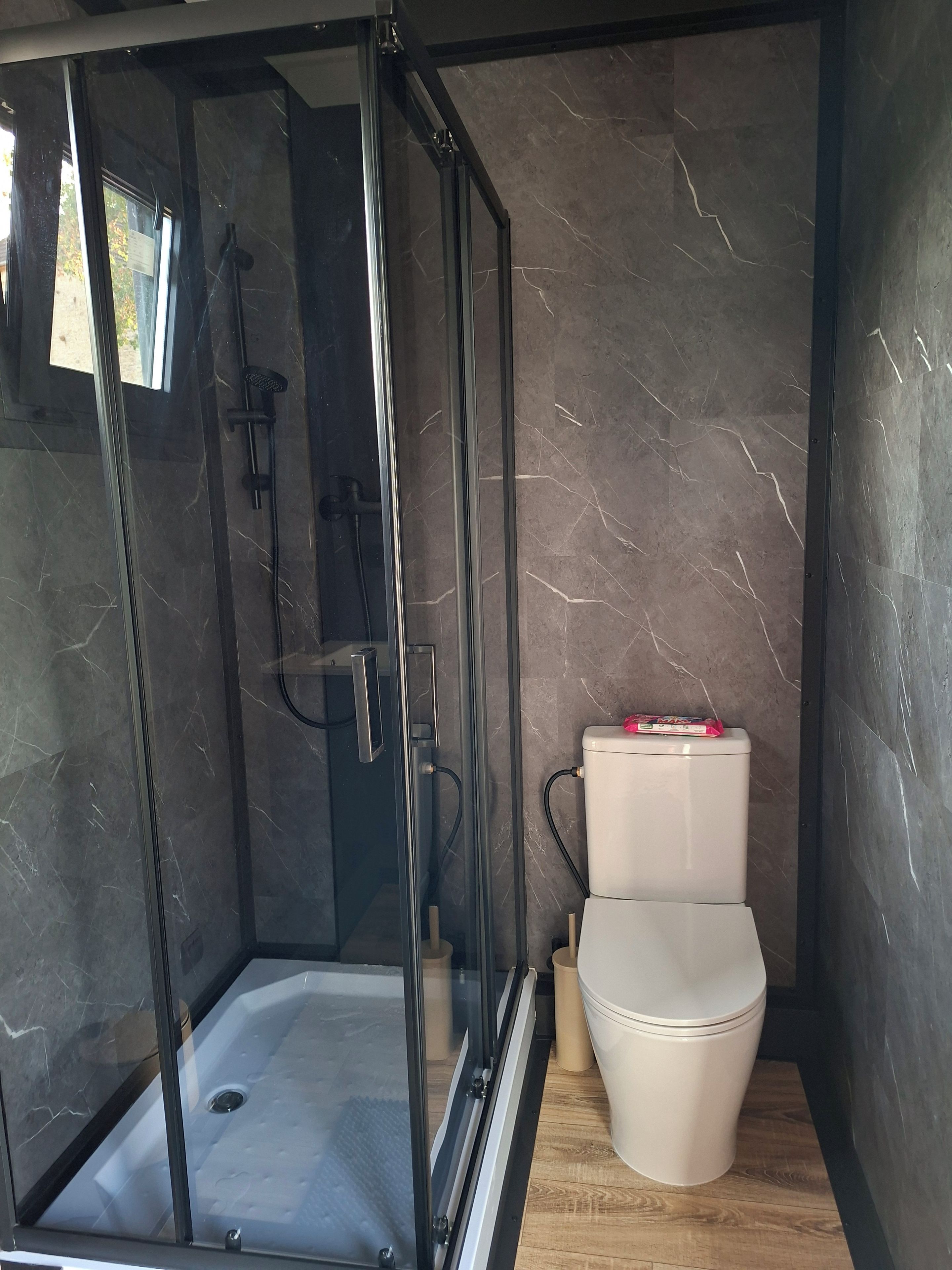 Ein modernes Badezimmer mit einer gläsernen Duschkabine, einer Toilette und Marmorwänden.