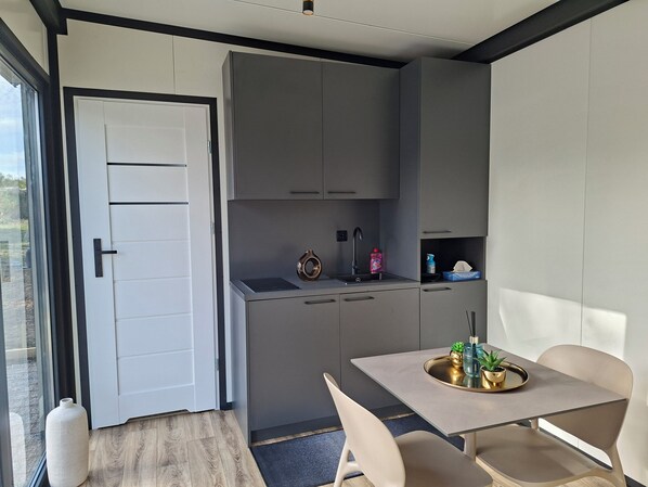 A compact kitchen with a dining area, a large window, and a door.