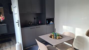 Une cuisine moderne avec des meubles gris, un évier et un coin repas comprenant une table et des chaises.