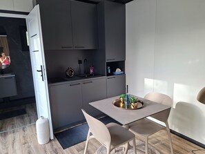 Une cuisine moderne avec des meubles gris, un évier et un coin repas comprenant une table et des chaises.
