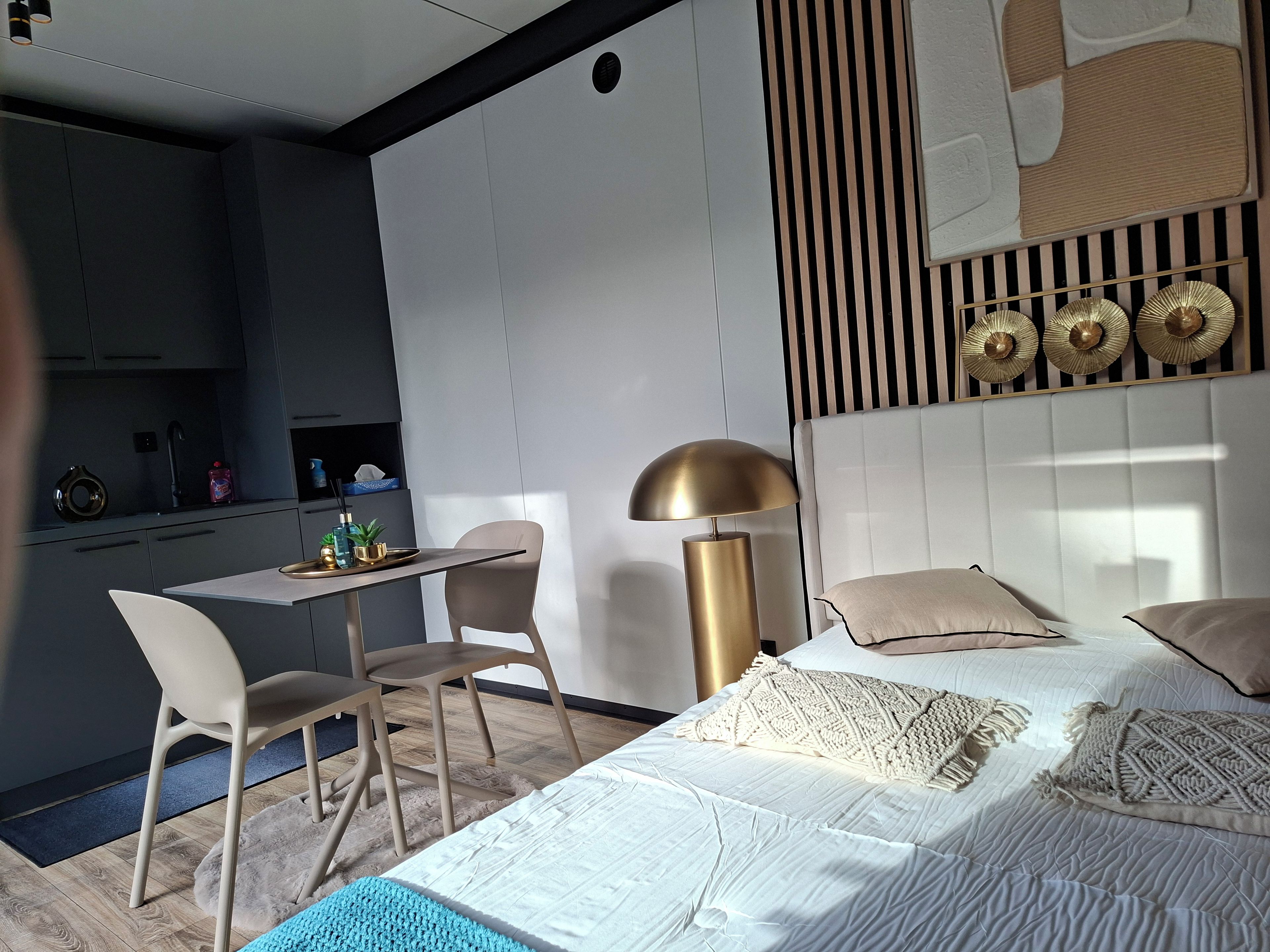 A modern bedroom with a bed, bedside tables, a desk, and a chair.