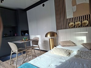 A modern bedroom with a bed, bedside tables, a desk, and a chair.