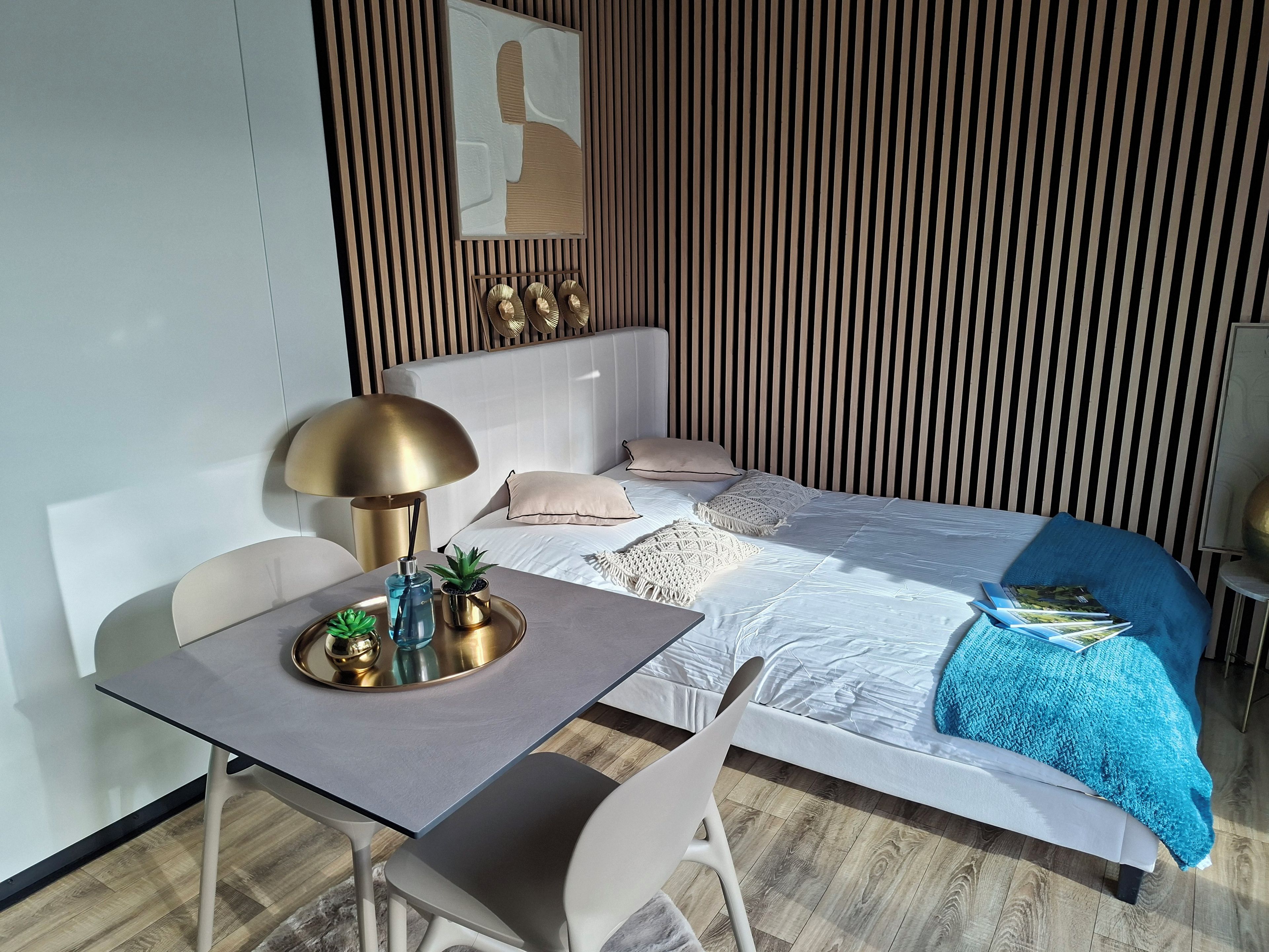 Une chambre d’hôtel moderne équipée d’un lit, d’une table de chevet, d’une lampe et d’une petite plante en pot.
