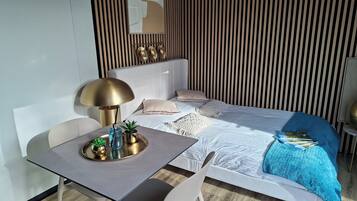 Une chambre d’hôtel moderne équipée d’un lit, d’une table de chevet, d’une lampe et d’une petite plante en pot.