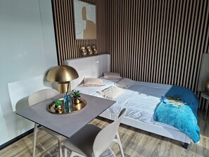 Une chambre d’hôtel moderne équipée d’un lit, d’une table de chevet, d’une lampe et d’une petite plante en pot.