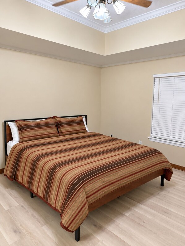 A bedroom with a bed, a ceiling fan, and a window with blinds. - The Southern Standard, Sleeps 6 (Brandon)