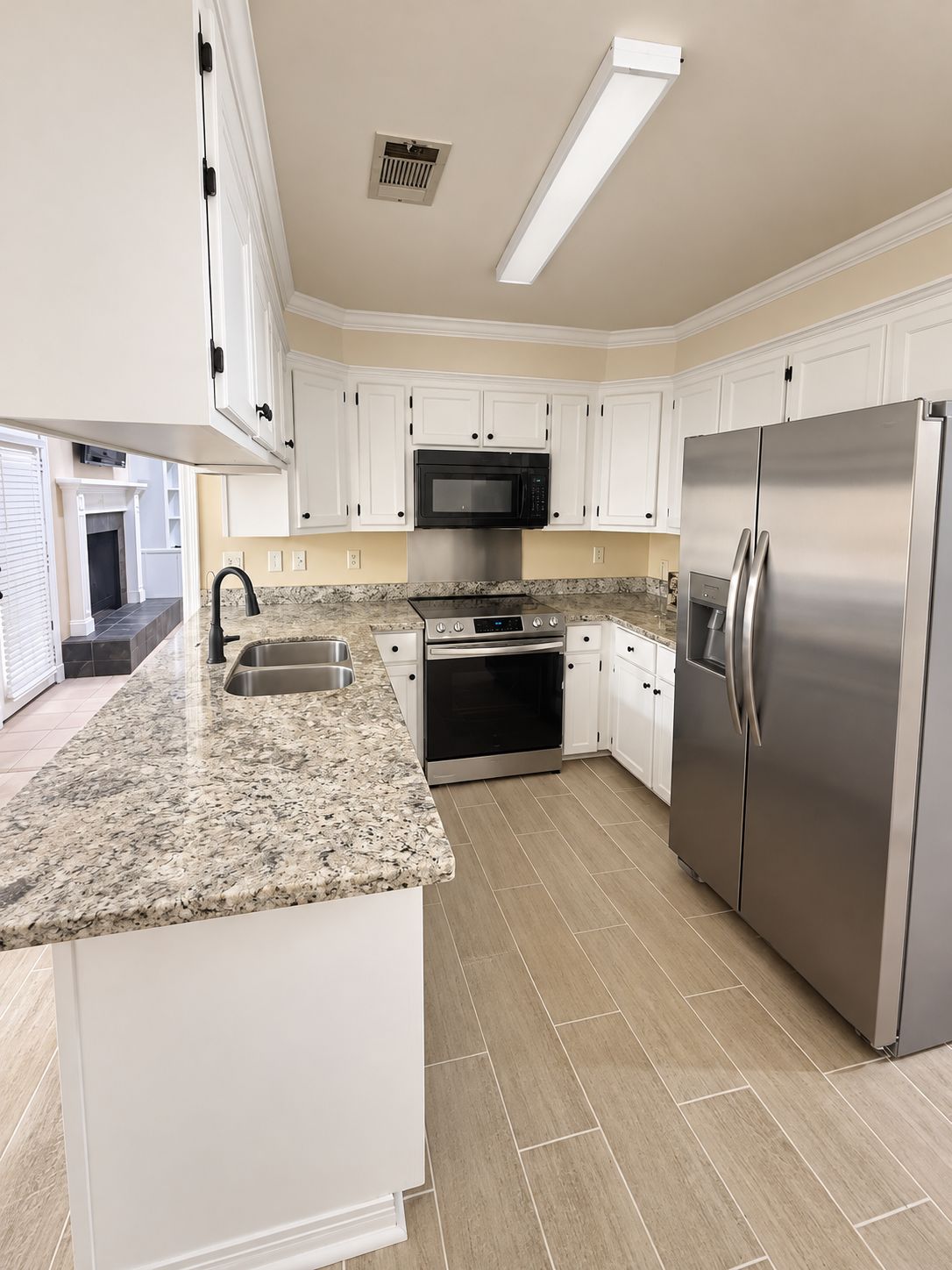 A modern kitchen with white cabinets, stainless steel appliances, and a granite countertop.
