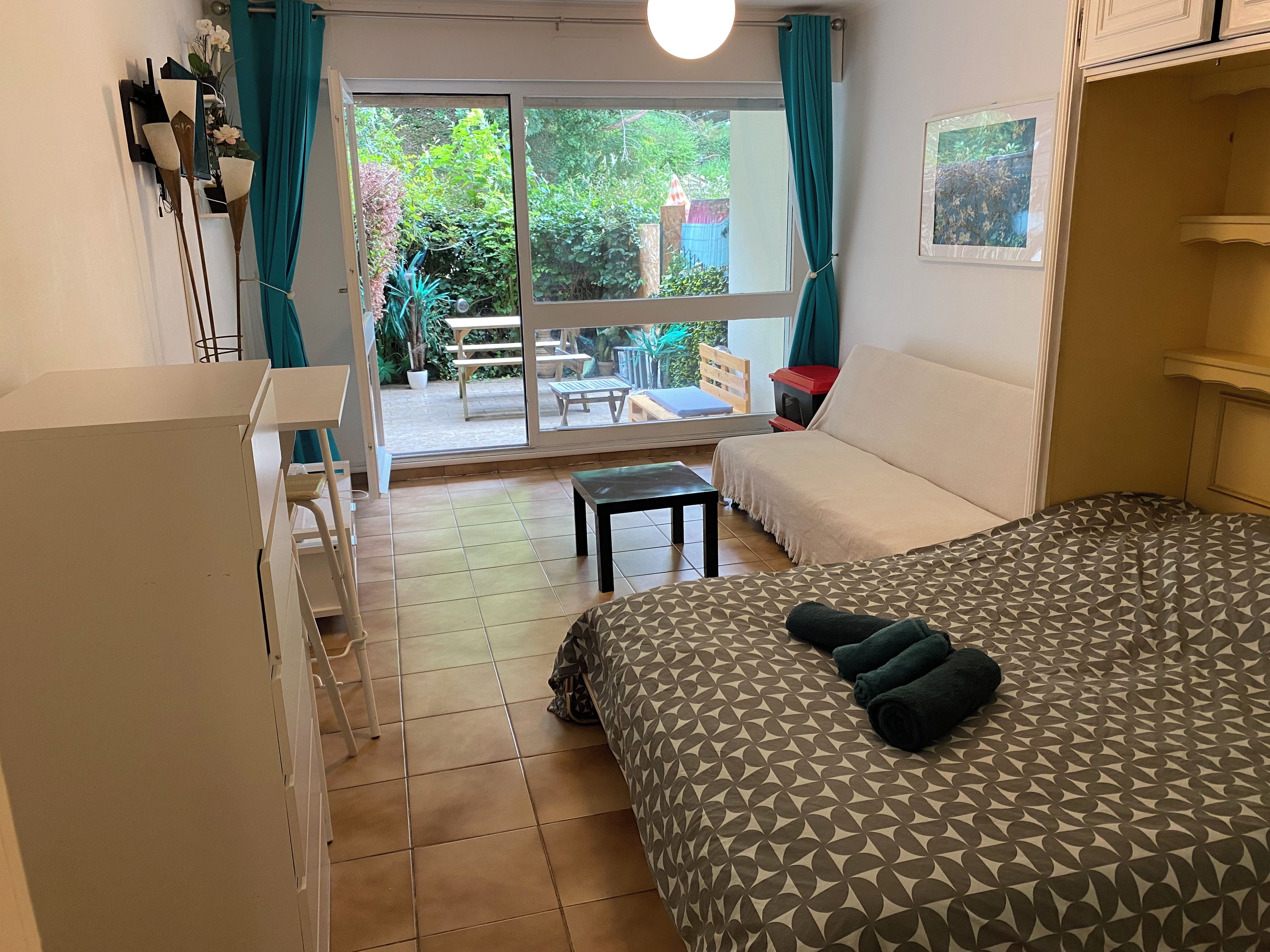 Ein Hotelzimmer mit einem Bett, einer Couch, einem kleinen Tisch und Blick auf den Garten durch das Fenster.