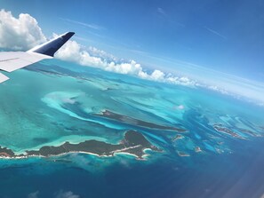 An airplane wing over a turquoise sea with clear skies. - Coming Soon, Spectacular Beachfront Villa, Bahama Bliss  (Wemyss)