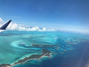 An airplane wing with a view of turquoise waters and cloud formations. - Coming Soon, Spectacular Beachfront Villa, Bahama Bliss  (Wemyss)