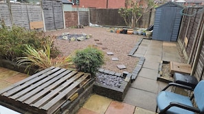 Ein Garten mit Kiesfläche, Holzterrasse und Kübelpflanzen.