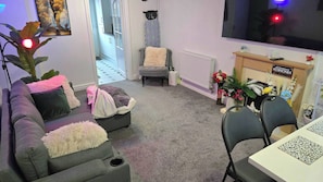 Ein Wohnzimmer mit grauem Sofa, einem kleinen Tisch, einem Fernseher und einer Heizung.