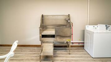 Een kamer met een roestvrijstalen spoelbak, een wasmachine en een stoel.