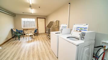A laundry room with two washing machines, a dryer, and a water heater. There is a window and a door in the background.