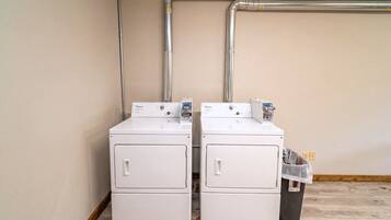 Two stacked white Whirlpool washing machines in a room with beige walls and wooden flooring.