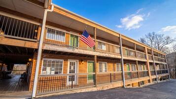 A multi-story log cabin with a balcony, an American flag, and a wooden exterior.