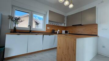 A modern kitchen with a central island, white cabinetry, and a wooden countertop.