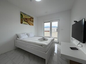 Un dormitorio moderno con una cama, un televisor y un cuadro en la pared.